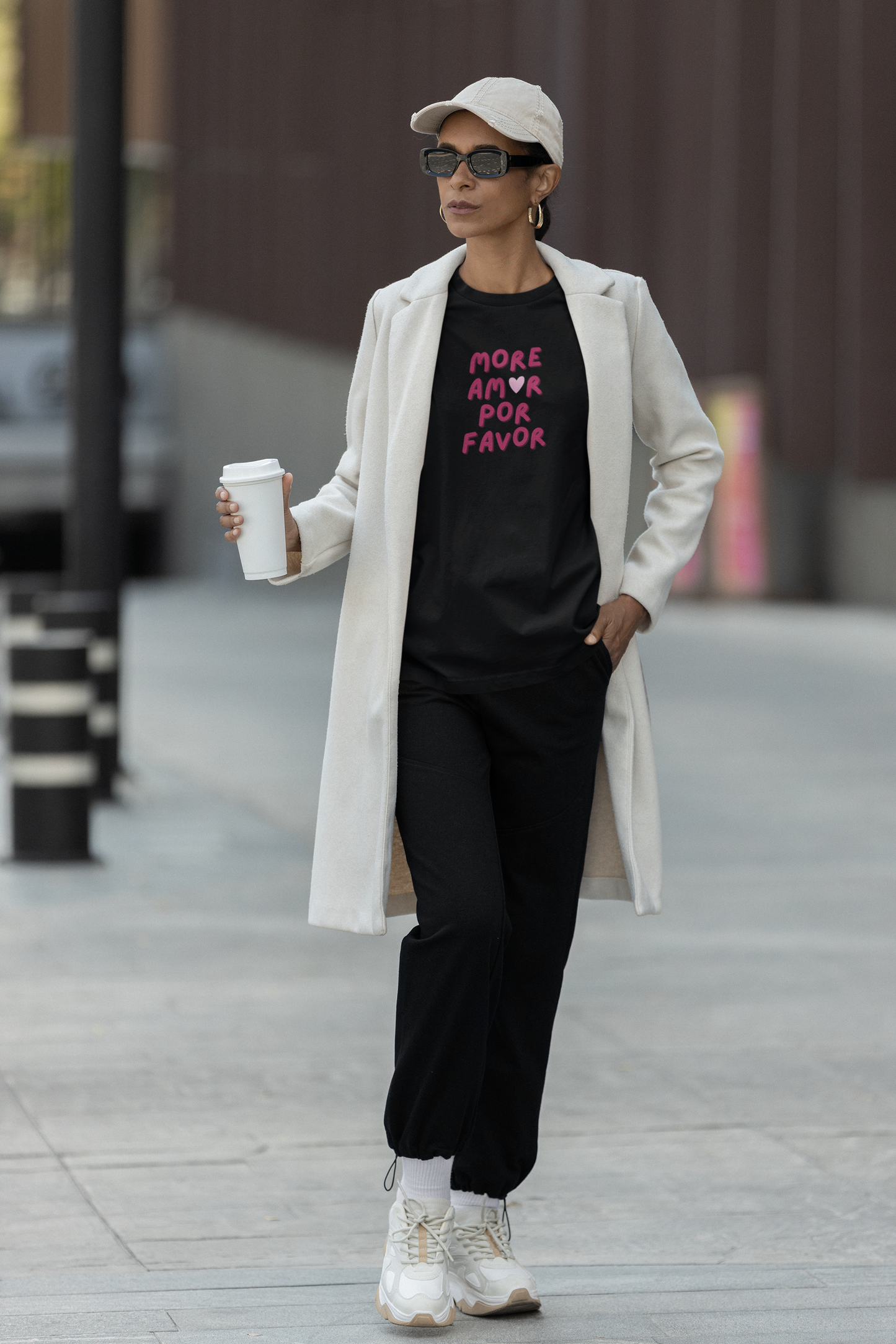 Frau mit Mantel trägt schwarzes „More Amor, Por Favor“ Shirt mit Herz, Statement für mehr Liebe, Malohana