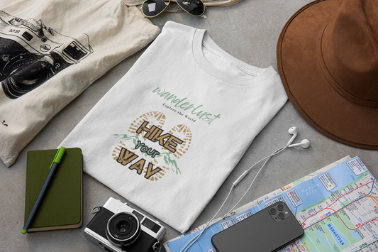 „Hike Your Way“ Shirt, liegt auf Tisch mit Kamera, Wanderlust-Motiv, Abenteuer erleben, Malohana